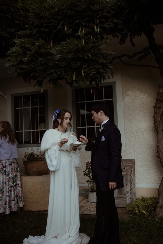 Braut und Bräutigam schneiden die Hochzeitstorte bei der Waldhochzeit Edelstauden, moody Hochzeitsfotografie Graz