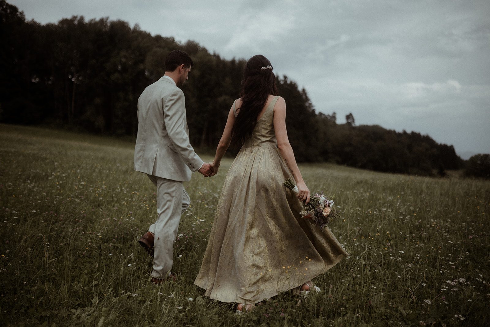 Ein Hochzeitspaar läuft über die Wiese
